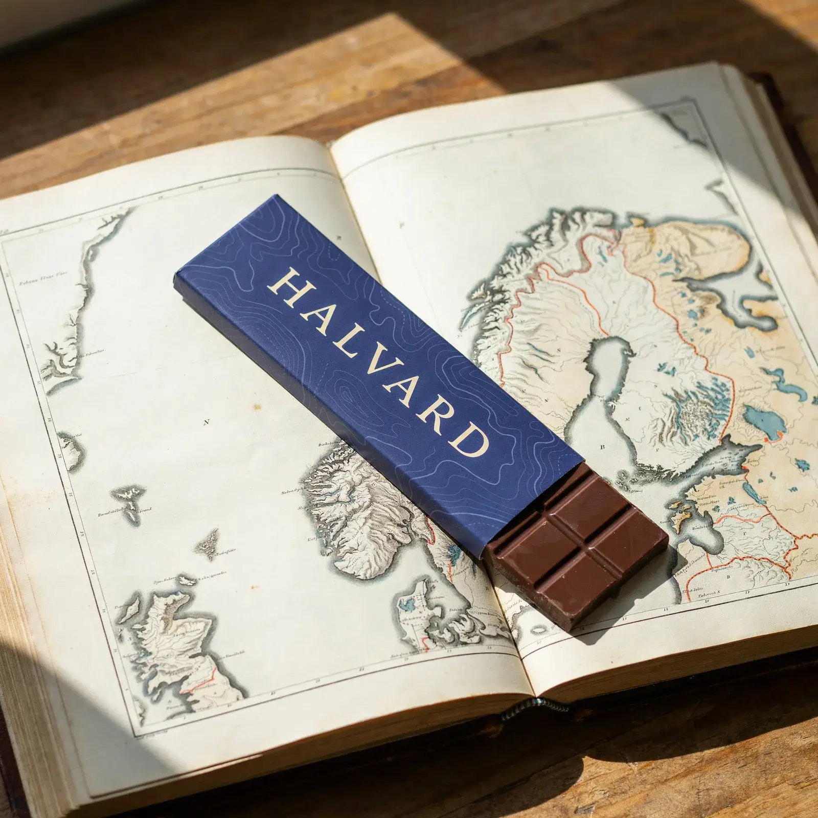 Halvard bar lying diagonally across an atlas of Norway, HALVARD running along the cobalt wrapper, the chocolate end showing