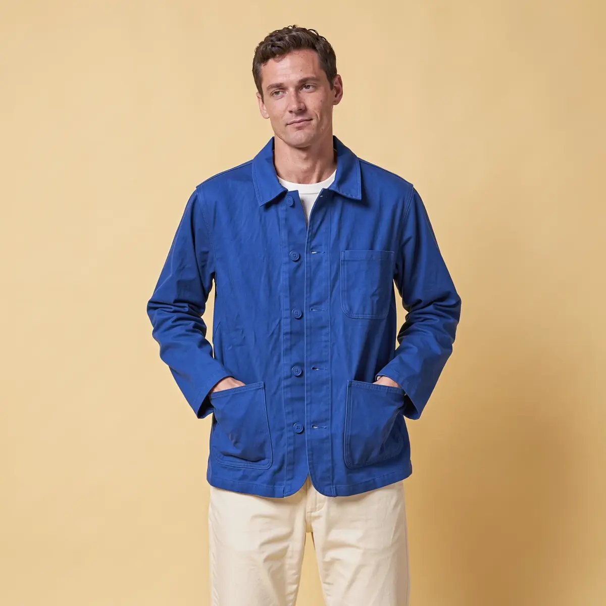 Flux 3 Image's run: a man in the cobalt chore jacket over a white T-shirt, hands in its hip pockets, on a yellow backdrop