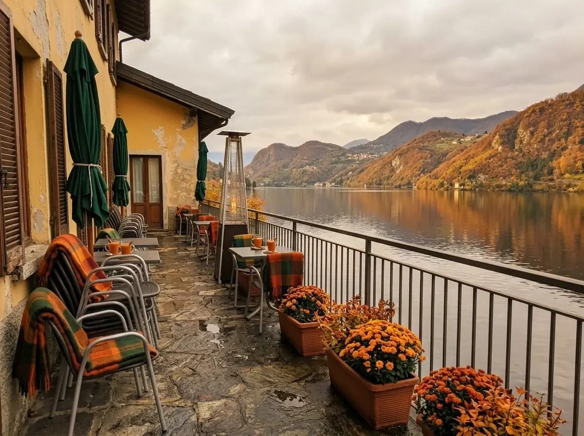 The same terrace edited by AI to autumn: plaid blankets on the chairs, a patio heater, orange chrysanthemums and golden hills across the lake