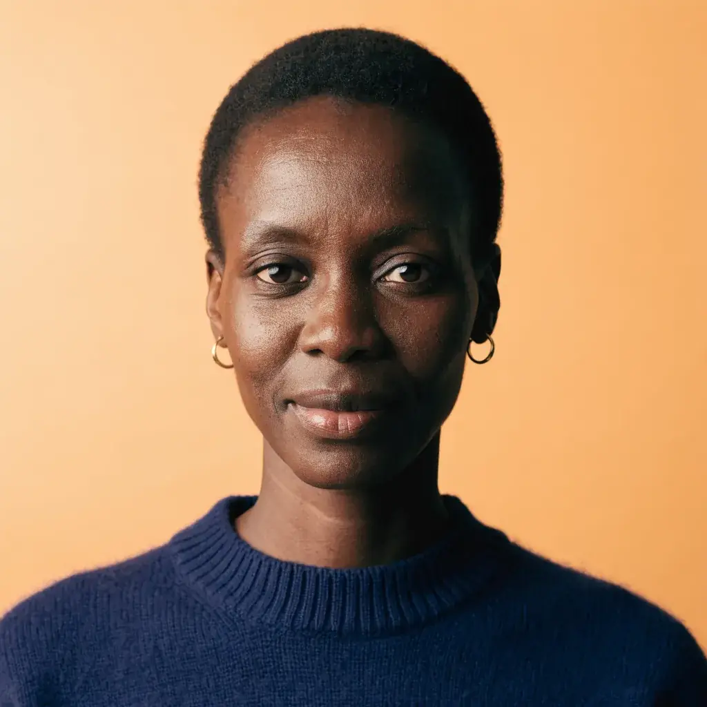 A woman with close-cropped hair, gold hoops and a navy sweater in higher contrast, the backdrop grading from light to dark, made on Recraft V4.1