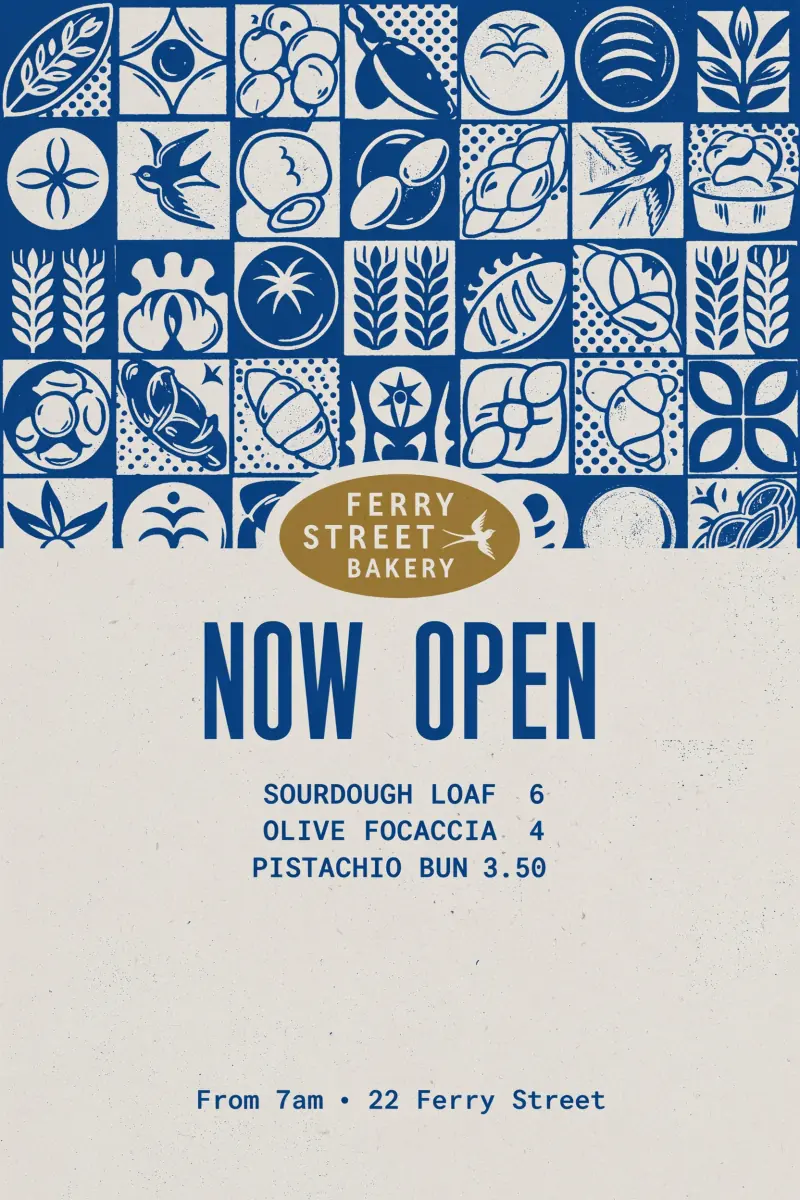 A cream opening poster for Ferry Street Bakery: a cobalt mosaic of loaves, croissants, wheat and swallows across the top, the name in a gold oval, NOW OPEN in tall cobalt capitals, three menu lines with prices, and From 7am · 22 Ferry Street at the foot