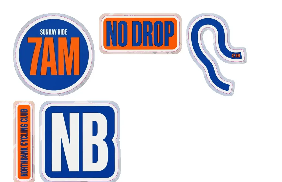 The top half of a Letter print sheet: the 7AM, NO DROP and route stickers in the first row, the club name strip and the NB monogram in the second, each with a thin pink cut line around its border